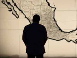 La sombra de un hombre se cierne de manera ominosa sobre el mapa de México.