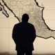 La sombra de un hombre se cierne de manera ominosa sobre el mapa de México.