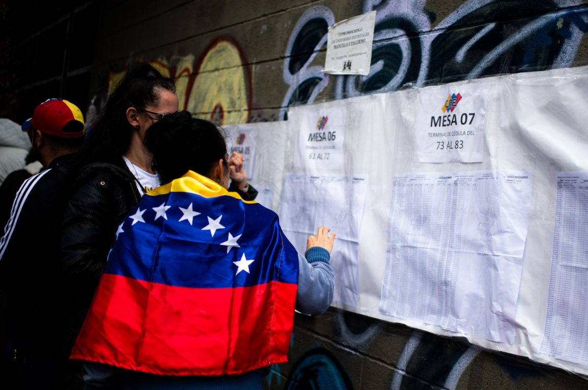 Dos personas buscan sus plazas de votación durante las elecciones del 28 de julio en Venezuela.